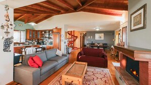 A spacious living room with a fireplace, a kitchen in the background, and a dining area. - Villa Oneirama - Nafplio Garden Retreat (Nafplio)