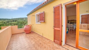A balcony with terracotta tiles, a red barrel, and wooden shutters. - La Teresina di Gallura: Crystal clear sea (Santa Teresa)