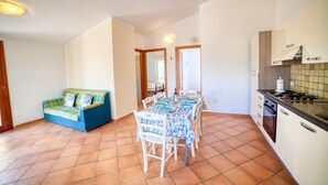 A compact kitchen with a dining table, a sofa, and a tiled floor. - La Teresina di Gallura: Crystal clear sea (Santa Teresa)