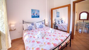 A bedroom with a bed, a mirror, and a painting of a sailboat. - La Teresina di Gallura: Crystal clear sea (Santa Teresa)