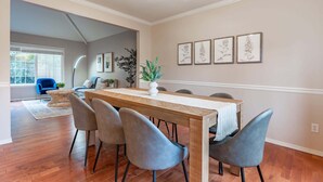 A dining area with a wooden table, six chairs, and a potted plant.