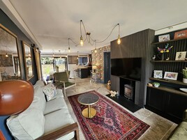 Una sala de estar moderna con un sofá, una mesa de centro redonda, una chimenea y un televisor.