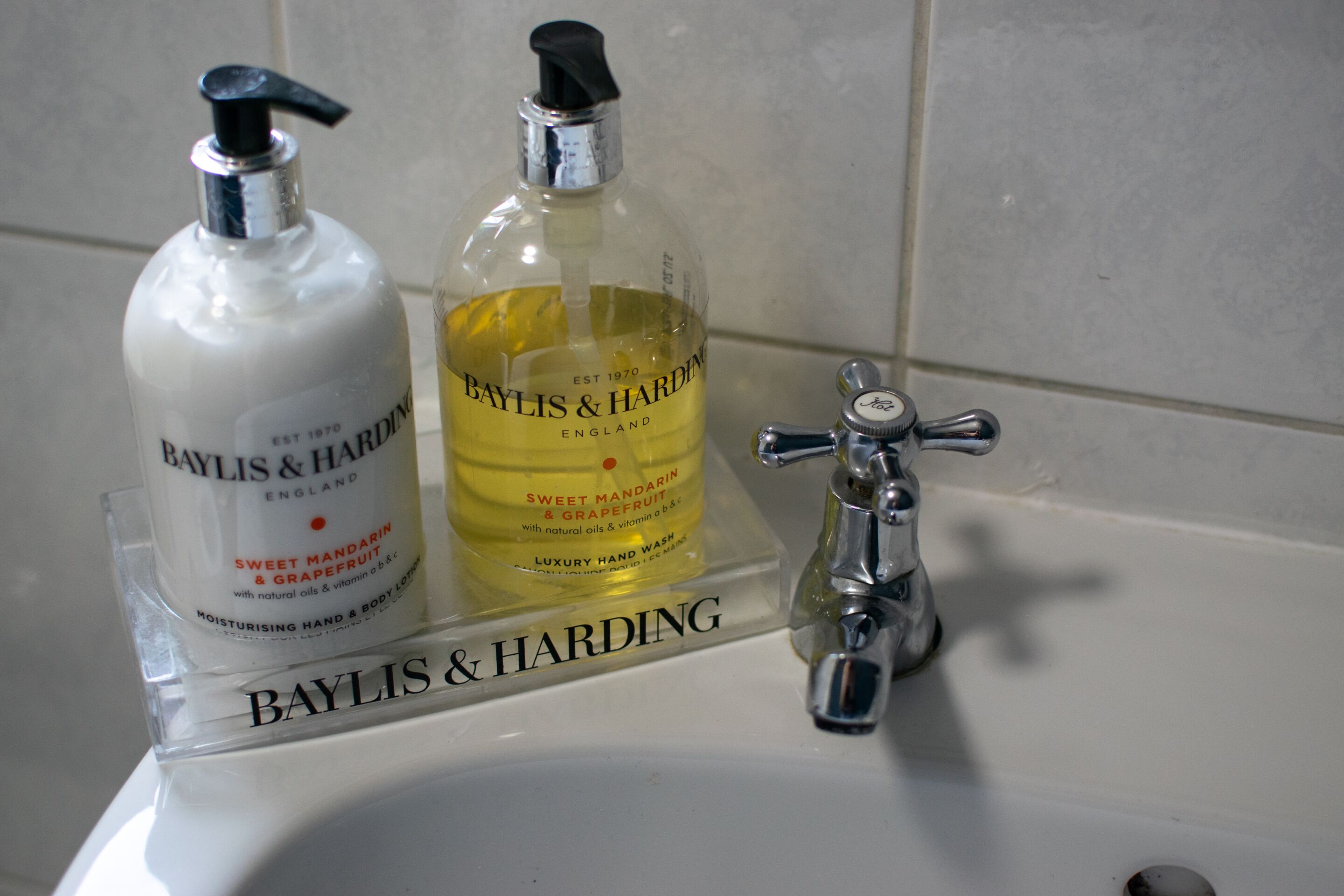Ett handfat i badrummet med två flaskor av Baylis & Harding-handtvål och en kromad kran.
