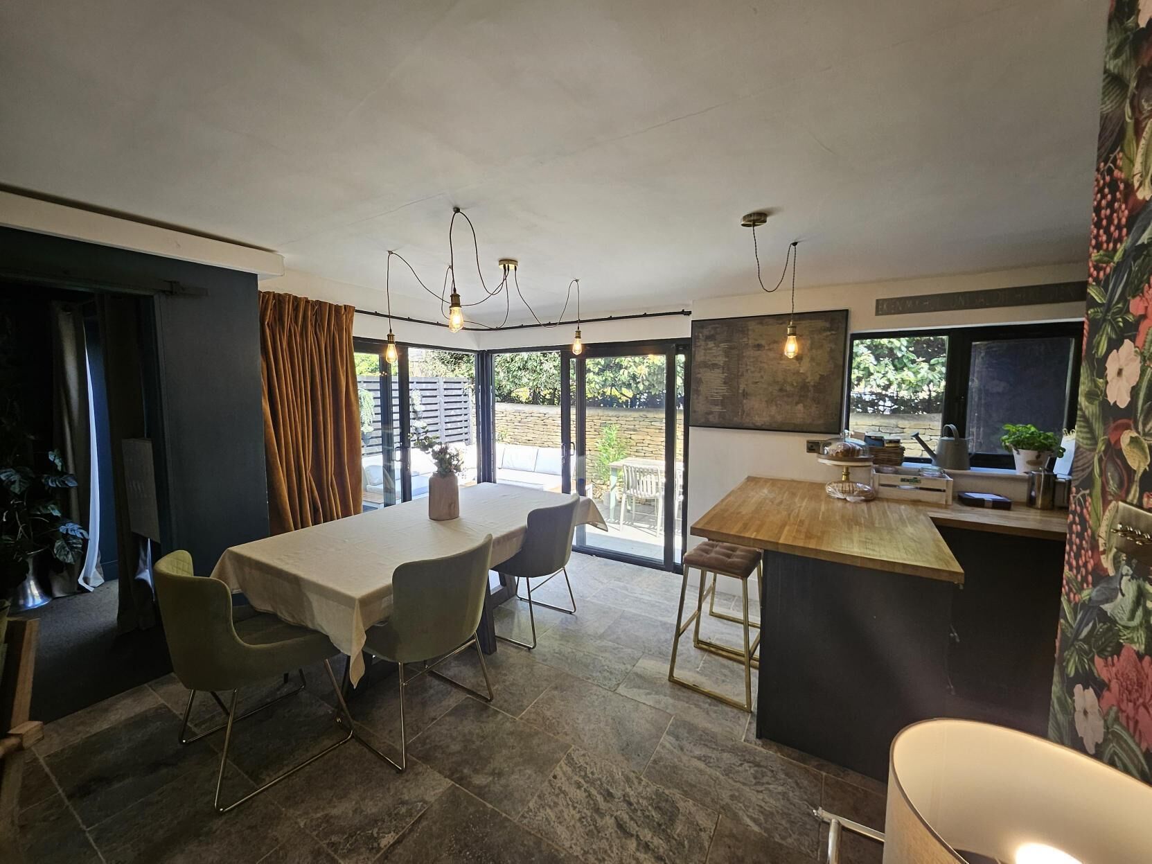 A modern kitchen with a dining area, large windows, and a view of the outdoors.