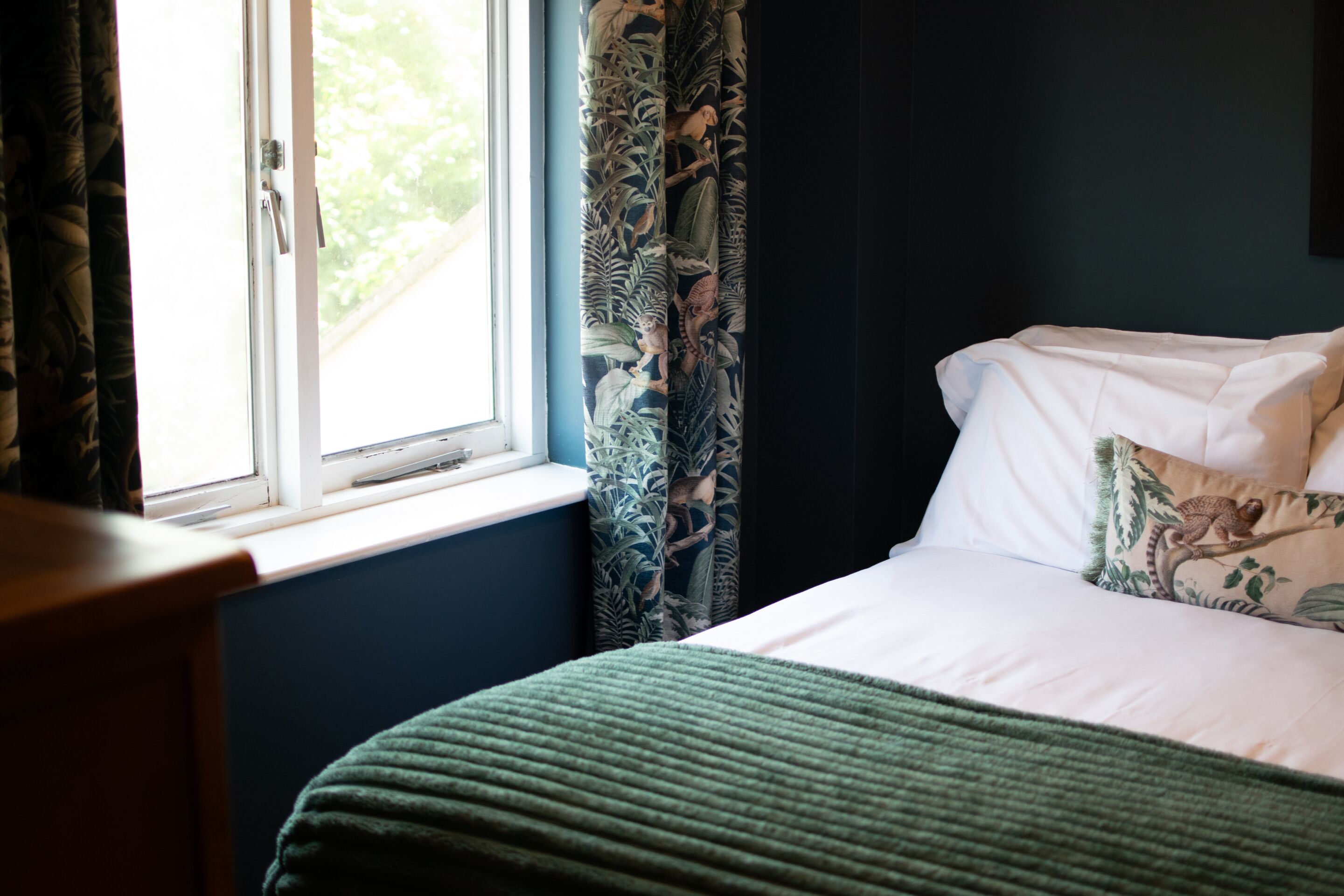 A bedroom with a bed, a window, and curtains.