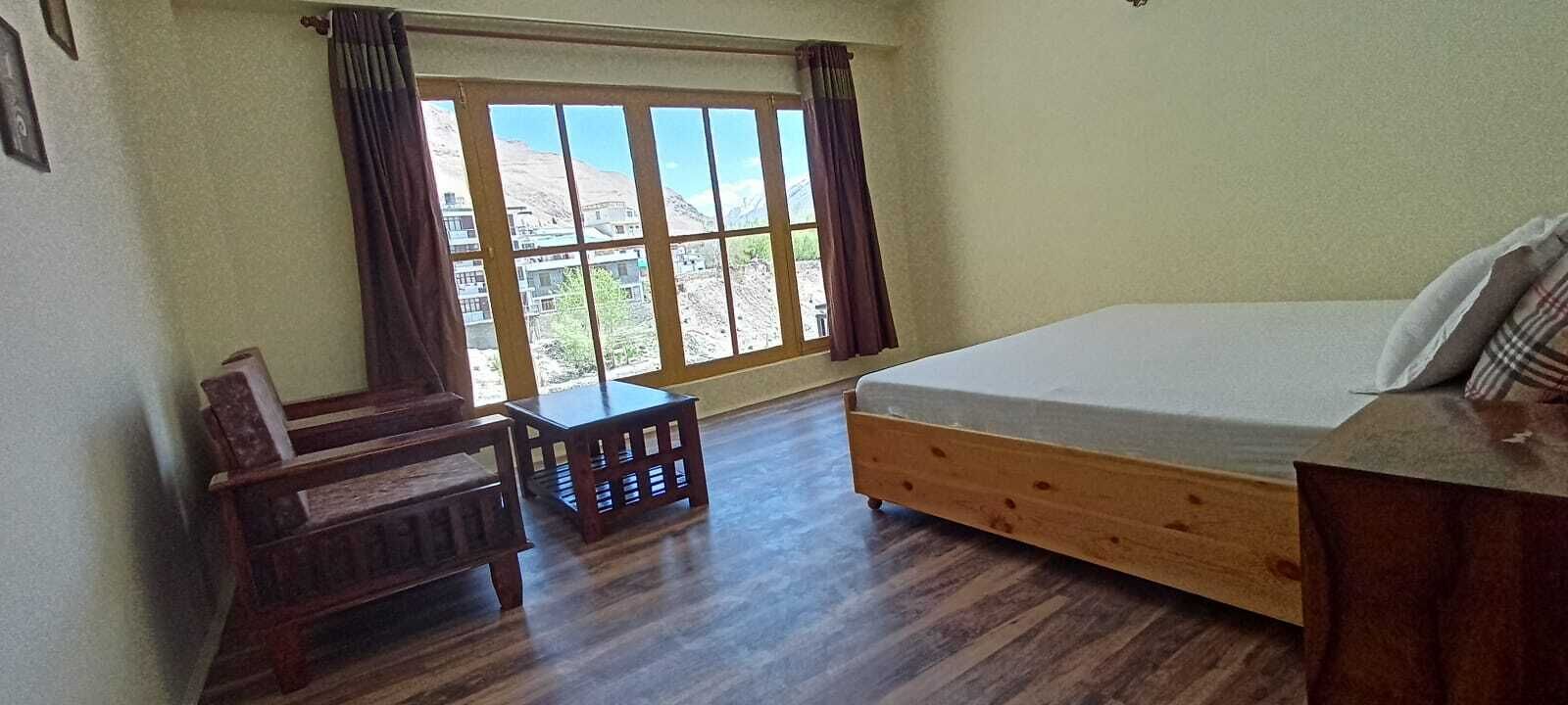 A room with a bed, a wooden desk, a chair, and a window with curtains.