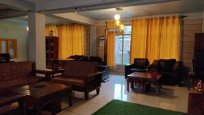 A spacious living room with a fireplace, a coffee table, sofas, and a green rug. - The old monk (Spiti)