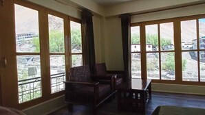 A room with large windows, a sofa, and a small table. - The old monk (Spiti)