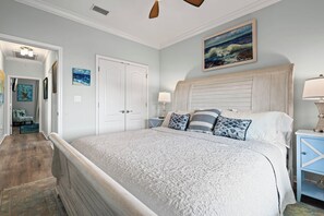 A bedroom with a large bed, a headboard, a nightstand, a lamp, and a painting on the wall.