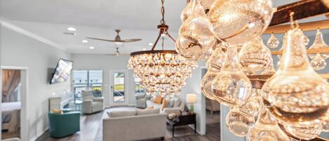 A spacious living room with a chandelier, a sofa, and a dining area.