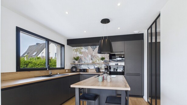 A modern kitchen with a large island, dark cabinetry, and a view of the outside through a window. - Modern house for 8 at 400m from the beach (Plouguerneau)