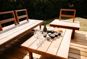Ein Holztisch für ein Picknick mit einer Champagnerflasche, mehreren Gläsern und einem Brotkorb.