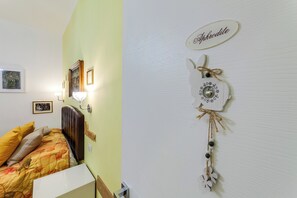 A bedroom with a bed, a nightstand, a lamp, and a wall decoration. - Sweet Stay Home (Rome)