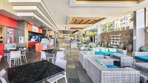 A hotel lobby with a central seating area, a bar, and a reception desk.