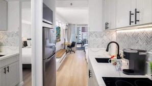 A modern kitchen with white cabinetry, a built-in oven, a coffee maker, and a dining area with a table and chairs.