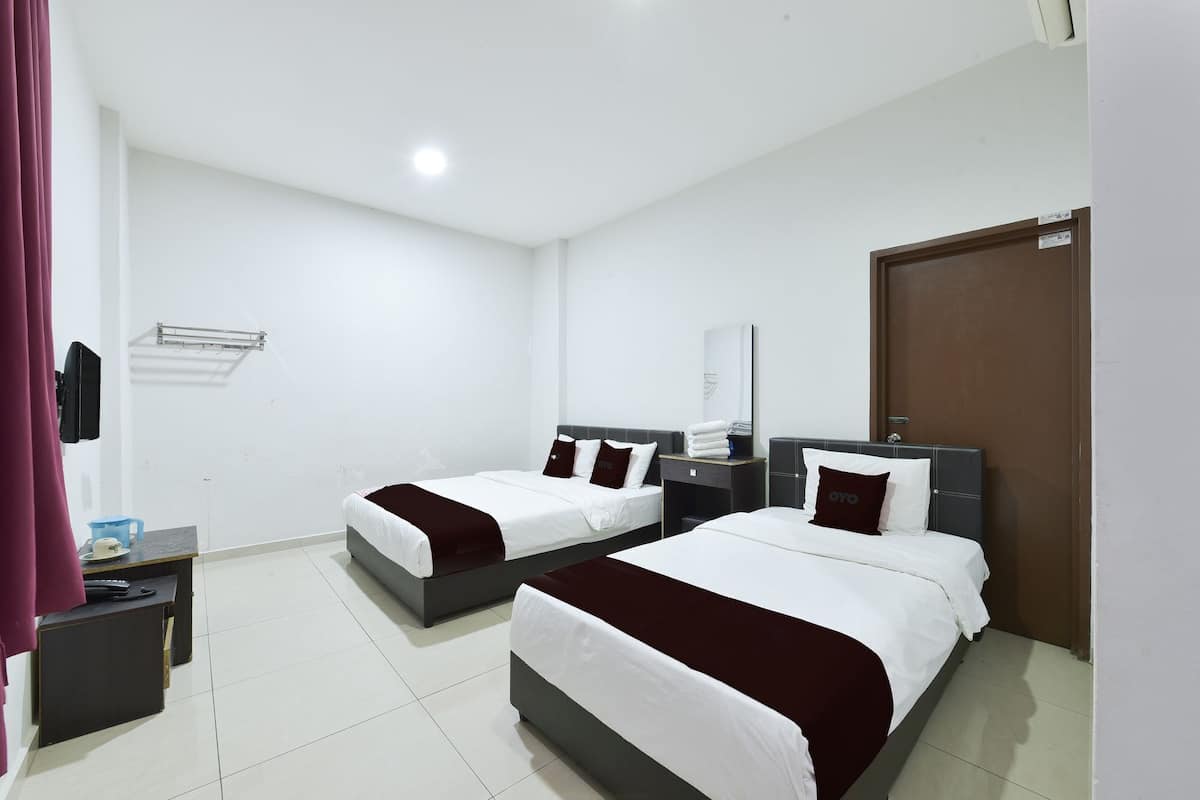 A hotel room with two beds, a desk, a chair, a wardrobe, and a door.