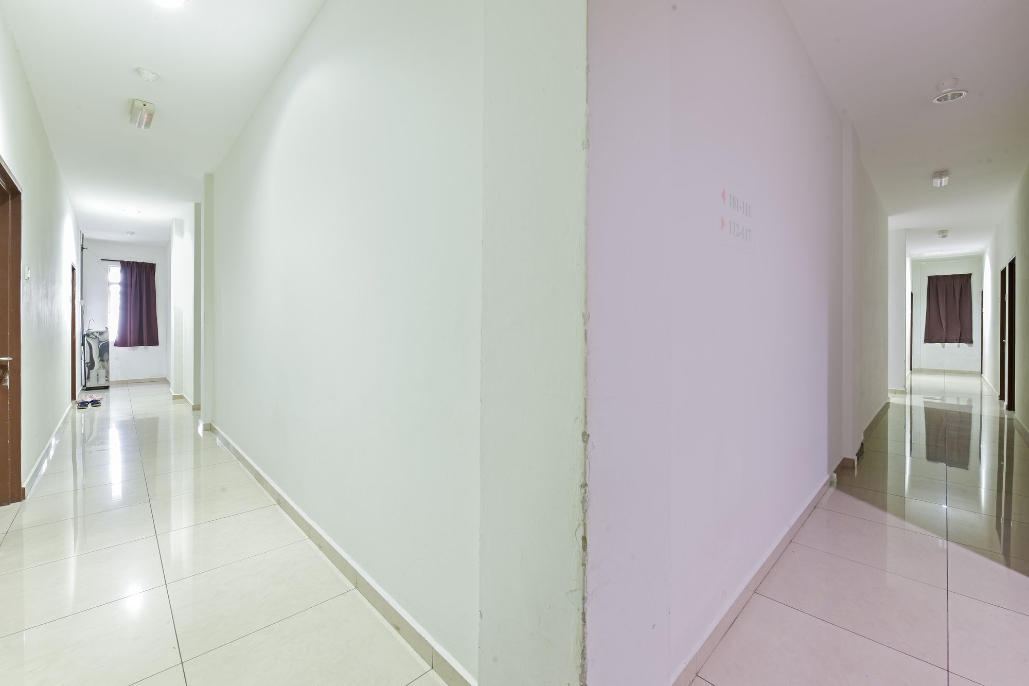 A long, narrow hallway with white walls and a tiled floor.