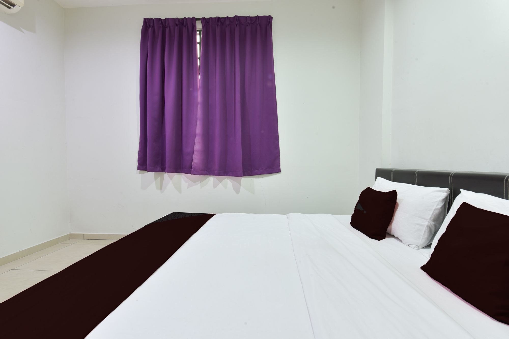 A bedroom with a bed, white bedding, and purple curtains.