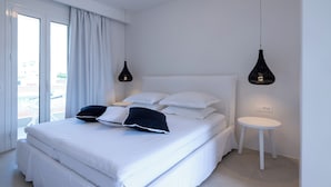 A neatly arranged bedroom with a large bed, two bedside tables, and a small white table. - Akrogiali Garden Hotel (Hersonissos)