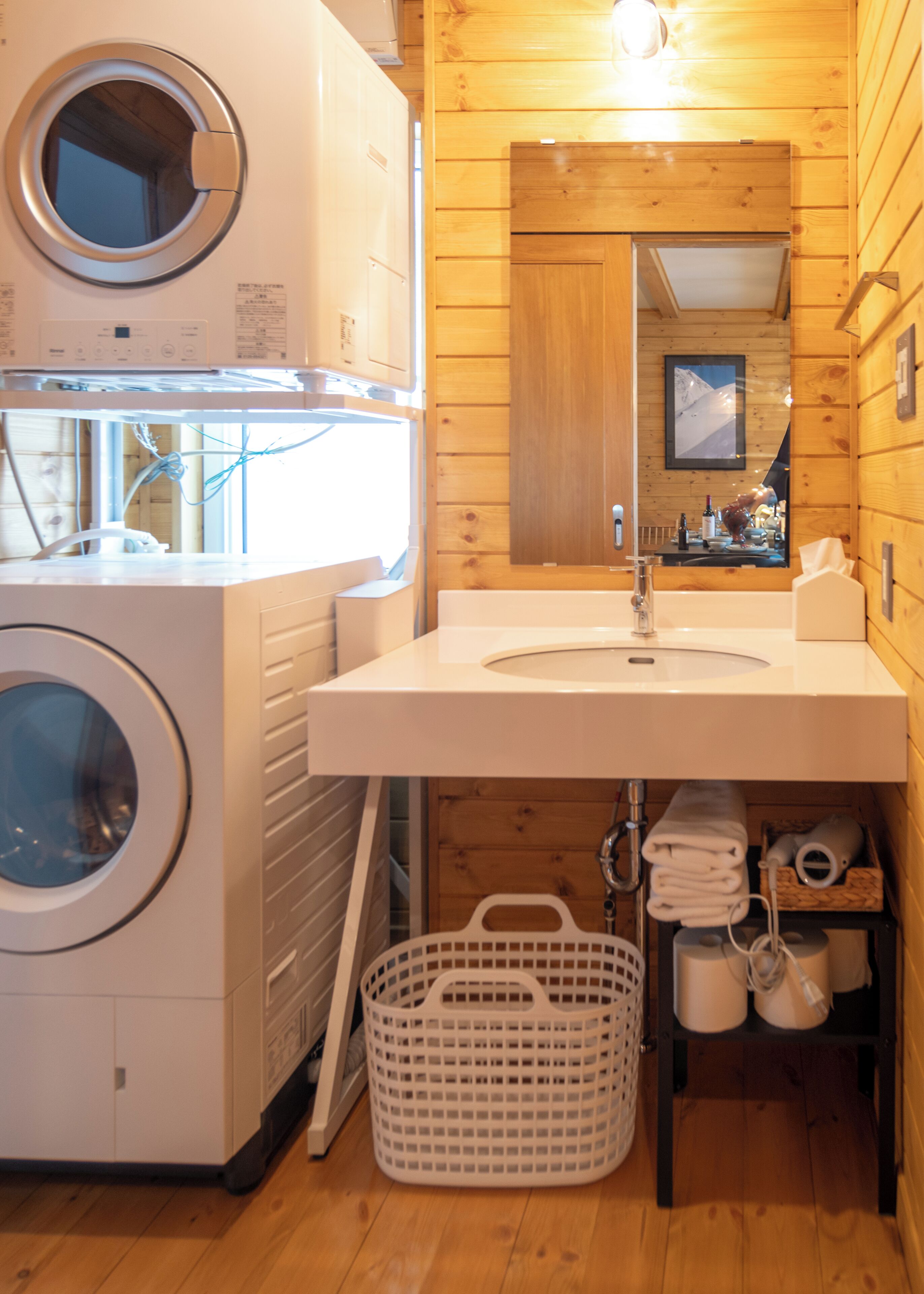 A compact laundry room with a washing machine, dryer, and a sink with a mirror above it.