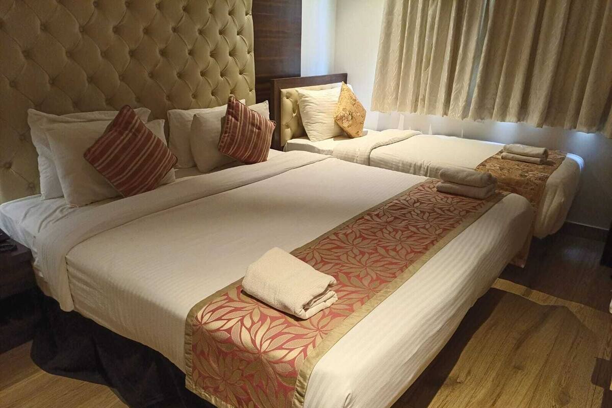 Ein Doppelbett mit floralem Überwurf, einem gepolsterten Kopfteil und mehreren Kissen.