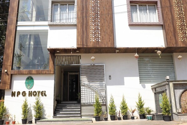 A hotel with a modern facade, a staircase leading to the entrance, and potted plants along the front.