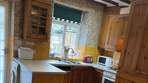 Una cocina con gabinetes de madera, un lavamanos, un microondas, un tostador y una ventana con vistas al exterior.