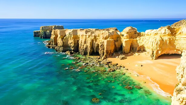 A coastal landscape with clear turquoise waters, sandy beach, and rocky cliffs. - Marina View 1 Bedroom Apartment w Swimming Pool (Albufeira)