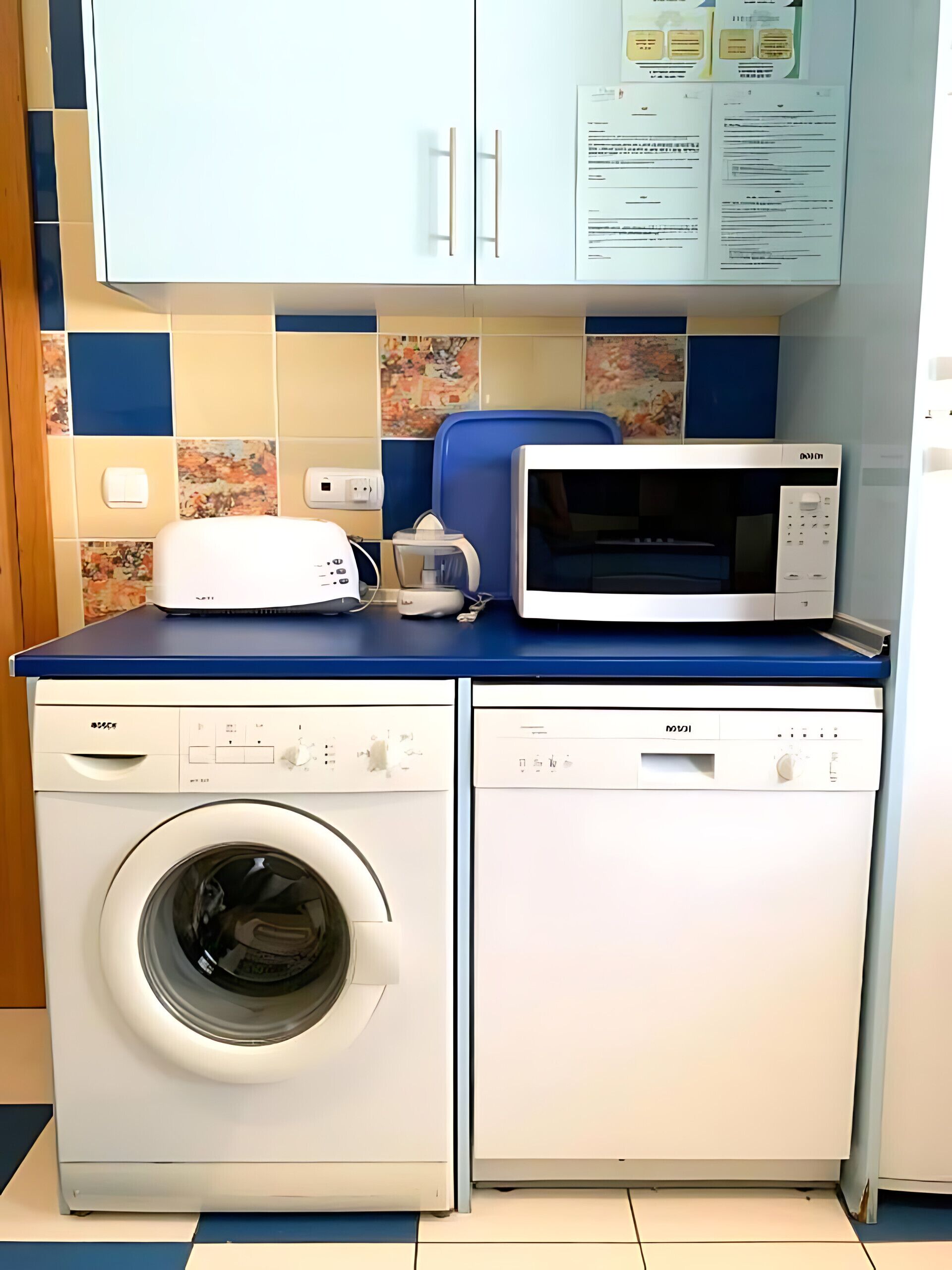 Uma área de lavanderia compacta com máquina de lavar, micro-ondas e lava-louças.
