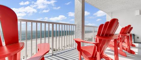 Un balcon avec des chaises rouges et une vue sur l’océan.