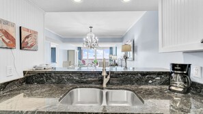 A kitchen with a double sink, a coffee maker, and a chandelier.
