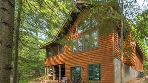 Eine Holzhütte mit Veranda, großen Fenstern und einem Steinweg, der zum Eingang führt.
