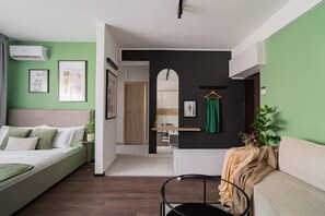 A modern bedroom with a bed, bedside table, and a green wall. - Cismigiu Park - Delightful and Fresh Studio (Bucharest)