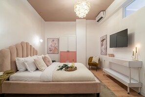 A modern bedroom with a large bed, a TV, a pink wardrobe, and a console table with candles. - Stunning 2BR With Balcony on Piata Universitatii (Bucharest)