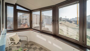 A corner room with large windows, a chair, and a checkered floor. - Vibrant & Spacious 3BR Condos on Amzei Square (Bucharest)
