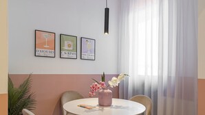 A dining area with a round table, four chairs, a vase with flowers, and three framed pictures on the wall. - Vibrant & Spacious 3BR Condos on Amzei Square (Bucharest)