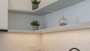 A modern kitchen with a white countertop, a black faucet, and a built-in oven. - Vibrant & Spacious 3BR Condos on Amzei Square (Bucharest)