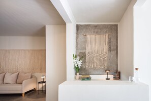 A modern living room with a sofa, a coffee table, and a wall-mounted macrame piece. - Casa Lumos - Minimalist Comfort Suites in Centro Historico (Oaxaca)