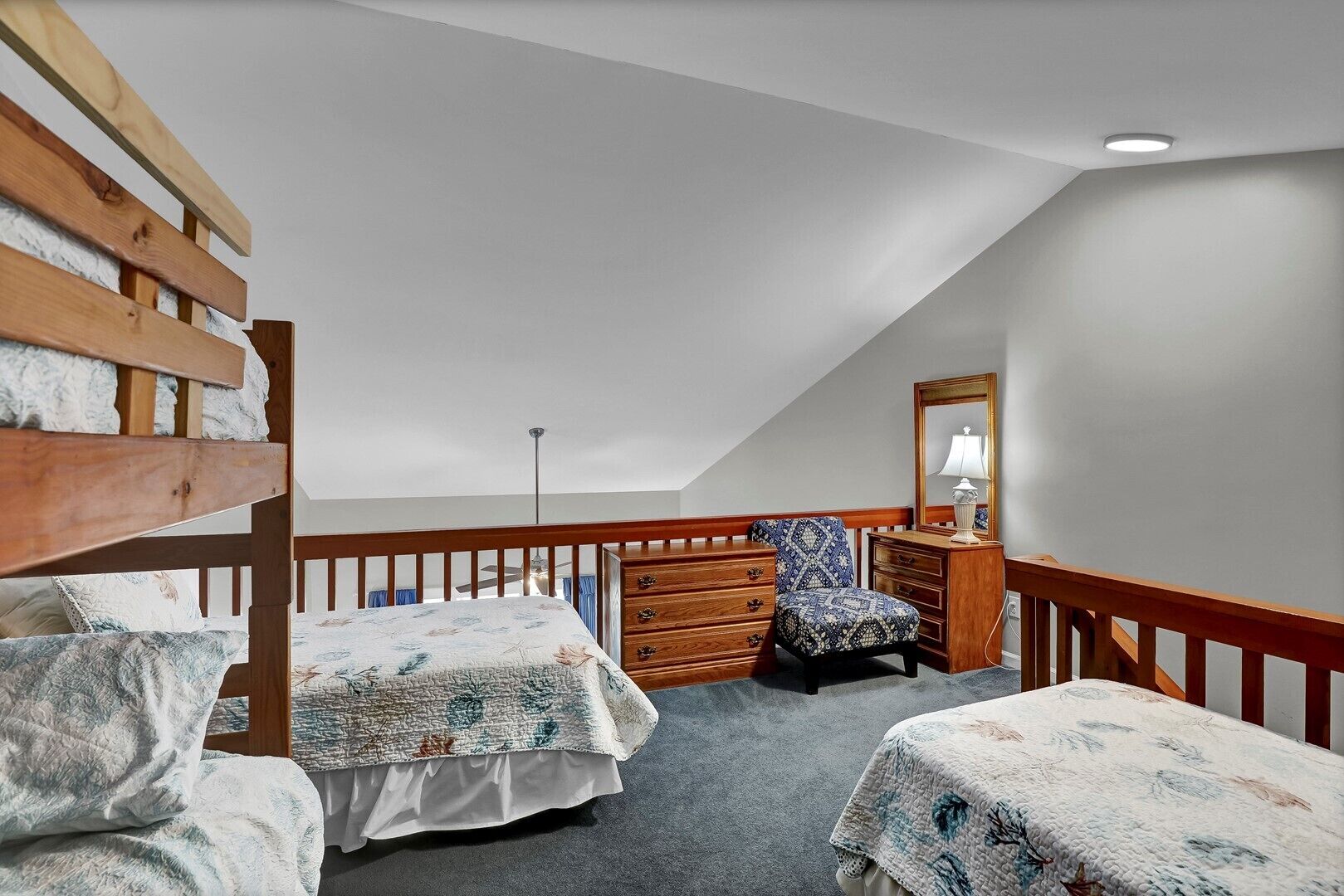 A bedroom with a bunk bed, a dresser, a chair, and a mirror.