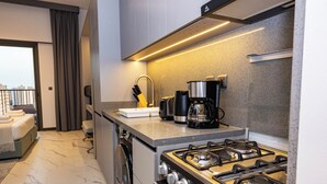 A modern kitchen with a gas stove, coffee maker, and a washing machine.