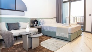 A modern hotel room with a bed, a sofa, a small table, and a nightstand.