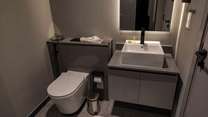 A compact bathroom with a toilet, sink, and mirror.