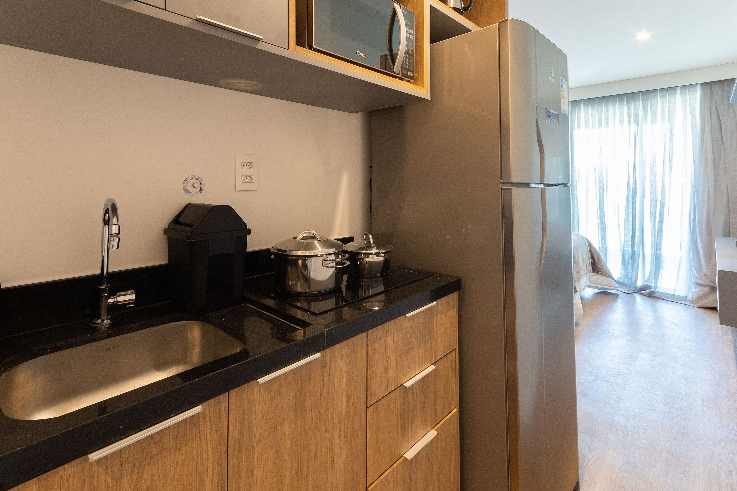 A modern kitchen with a stainless steel sink, wooden cabinets, and a built-in microwave.