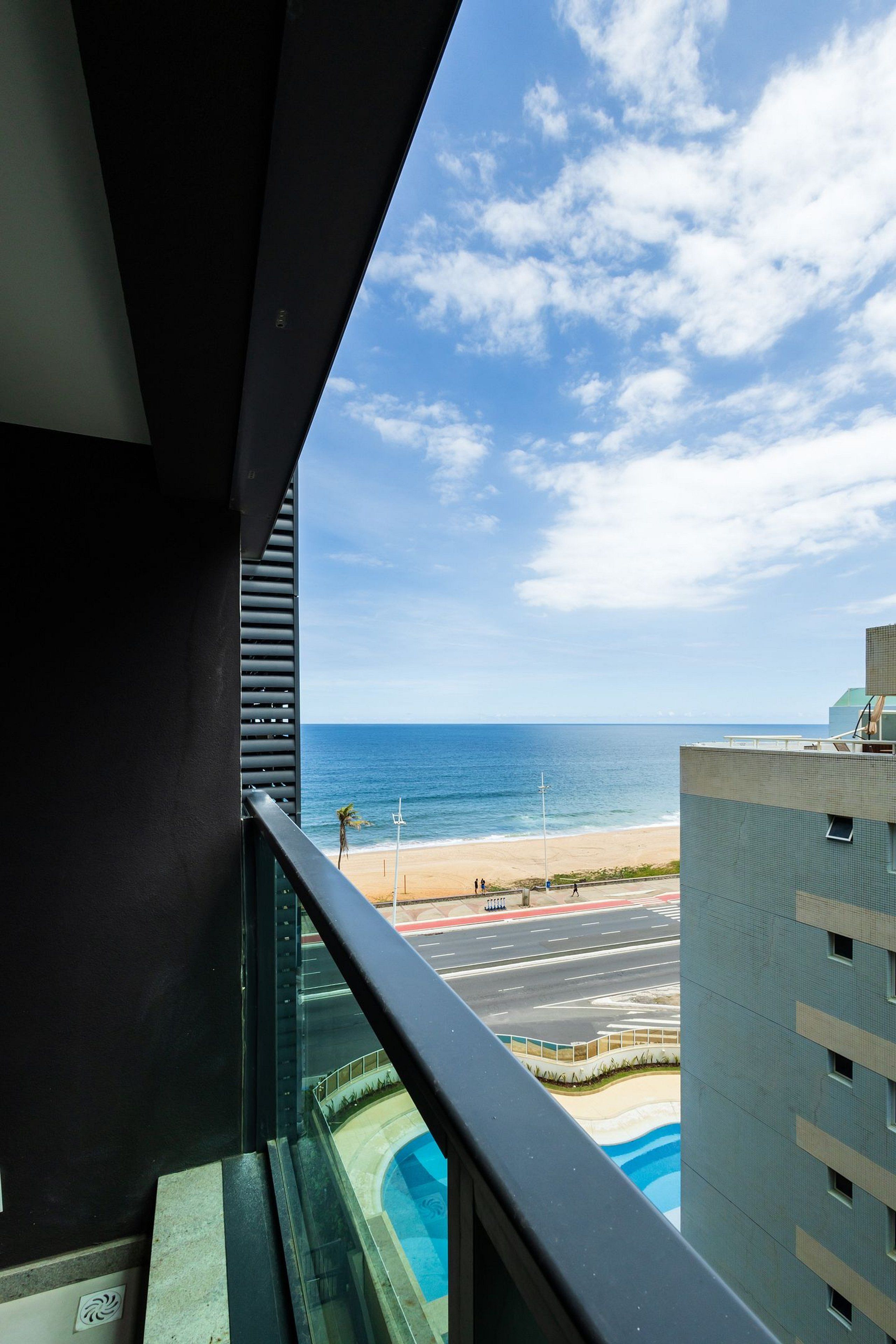A view from a balcony overlooking a beach with a clear sky and calm sea.