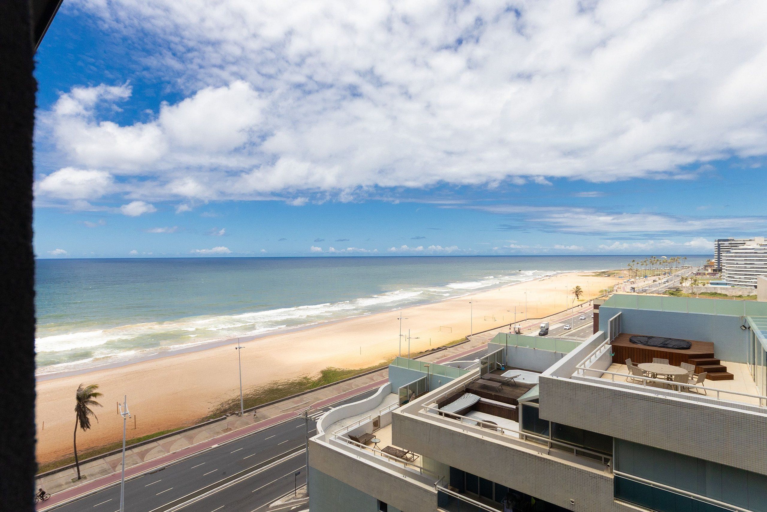 A view of a beach from a building with a rooftop patio.