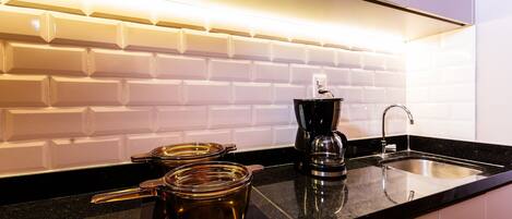 A modern kitchen with a black countertop, a coffee maker, and a kettle.