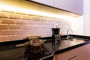 A modern kitchen with a black countertop, a coffee maker, and a kettle. - Art Studio Housi Salvador by Carpediem (Salvador)