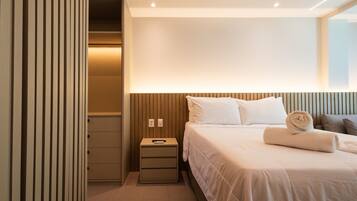 Ein Hotelzimmer mit einem ordentlich bezogenen Bett, einem Nachttisch mit Fernbedienung und einer Wandleuchte.