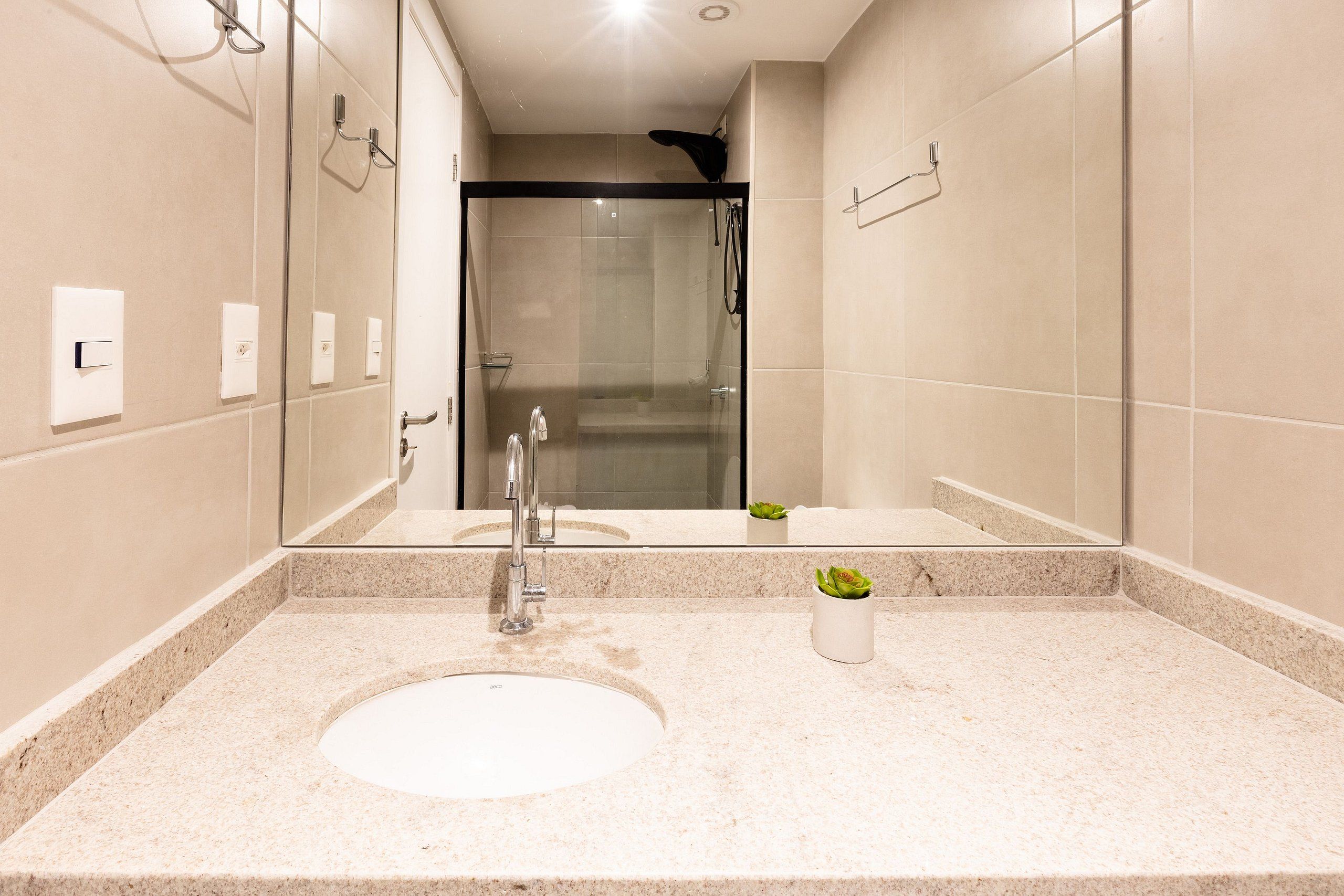 Un bagno moderno con uno specchio grande, un lavandino e una zona doccia.