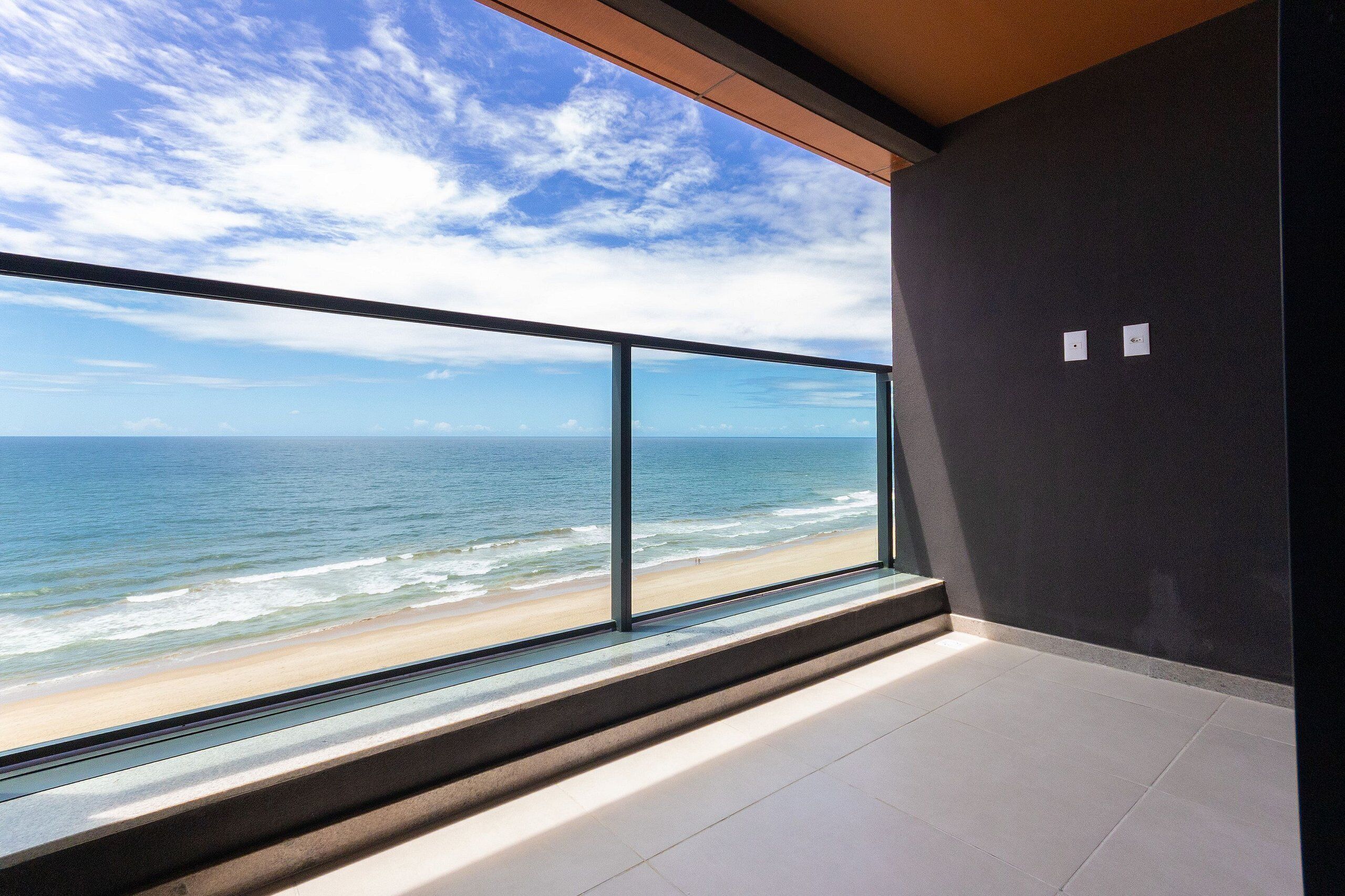 A modern room with a large window overlooking a beach and ocean.